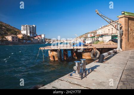 Vista sulla costa con attrezzature portuali. Baia di Balaklava, paesaggio estivo. Si tratta di un insediamento sulla penisola di Crimea e parte della città di Sevastopol Foto Stock