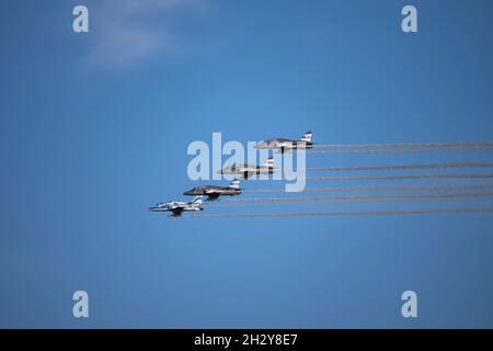 Un'inquadratura ad angolo basso di quattro aerei militari con percorsi fumogeni nel cielo azzurro e limpido Foto Stock