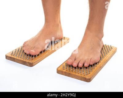 Foto di un maschio piedi in piedi su un asse con unghie affilate su sfondo bianco. Tavola di Sadhu - pratica yoga. Dolore, prove, salute, rilassamento, cogniti Foto Stock