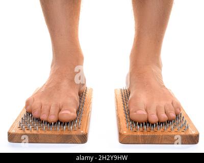 Vista frontale di un maschio piedi in piedi su un asse con unghie affilate su sfondo bianco. Tavola di Sadhu - pratica yoga. Dolore, prove, salute, rilassamento, co Foto Stock