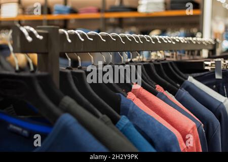 Shopping da vicino su grucce. Negozio di abbigliamento maschile con una varietà di articoli autunno-inverno tra cui scegliere. La gamma di prodotti nella boutique. T Foto Stock