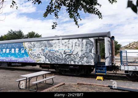 Un vagone ferroviario per passeggeri dipinto dall'alto verso il basso con opere d'arte si trova presso la stazione Lamy Amtrak di Lamy, New Mexico, appena a sud di Santa Fe. La Canzone Di fuoco A. Foto Stock