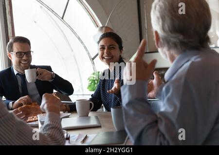 Il personale multietnico, cordiale e felice, è lieto di gustare la pizza in ufficio Foto Stock