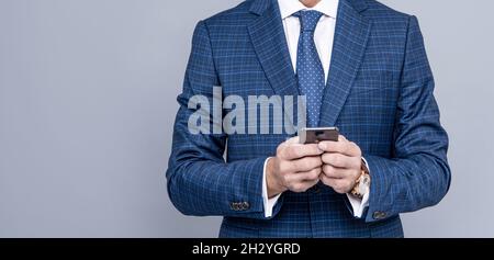 uomo d'affari tagliato in vestito che digita il messaggio di testo sul telefono, spazio di copia, comunicazione di affari Foto Stock