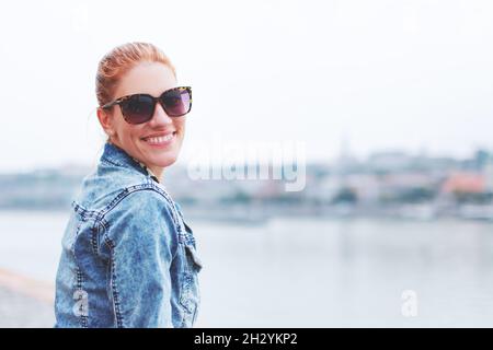 Felice giovane rossa caucasica donna toothy sorriso a riva al fiume Foto Stock