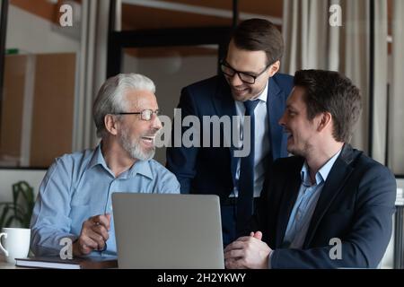 Sorridenti colleghi maschi di diverse età si divertono al computer Foto Stock