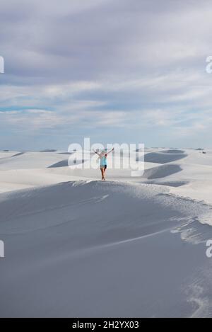 Una vista posteriore di una donna felice su dune di sabbia ricoperte di neve Foto Stock