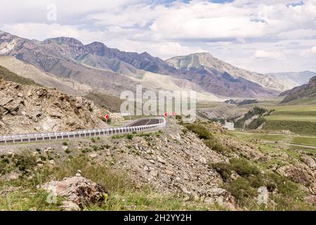 Pericolosa strada di montagna tortuosa lastricata nelle rocce tra il crinale e il fiume. Il tratto di Chuisky corre tra la catena montuosa di Saldzhar e la Foto Stock