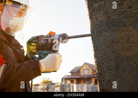 Un attrezzo di montaggio maschio funziona con un martello perforatore. Lavori di costruzione. Foto Stock