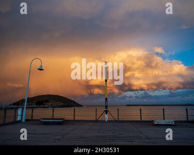 Tempesta sull'isola di Muttonbird, nuvole arancioni scintillanti, vista dalla fine del molo Jetty che guarda al mare, Coffs Harbour NSW Australia Foto Stock