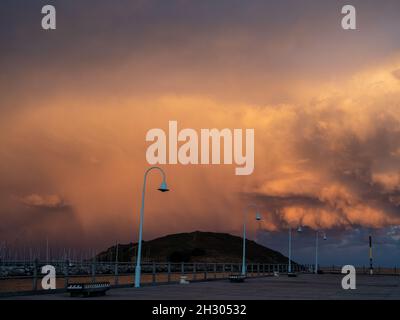 Tempesta che si fermenta sull'isola di Muttonbird, nuvole arancioni incandescenti, vista dalla fine del molo Jetty, Coffs Harbour NSW Australia Foto Stock