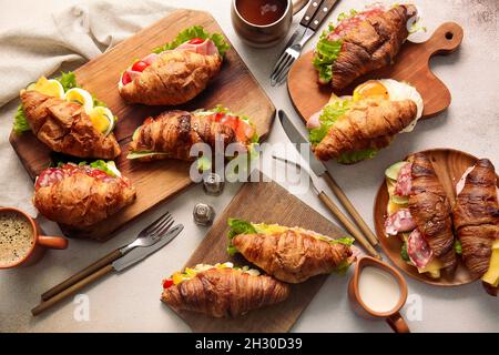 Tavole di legno con deliziosi croissant sandwich su sfondo bianco Foto Stock