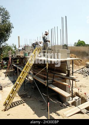 Massoni di calcestruzzo che costruisce un muro di blocco su impalcatura Foto Stock
