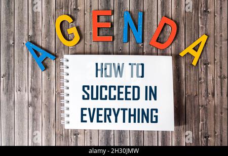 Il testo COME RIUSCIRE IN TUTTO è scritto su un taccuino ed un concetto di .Business del tavolo di legno. Foto Stock