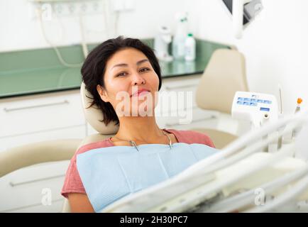 Donna asiatica felice seduta in sedia dentale Foto Stock