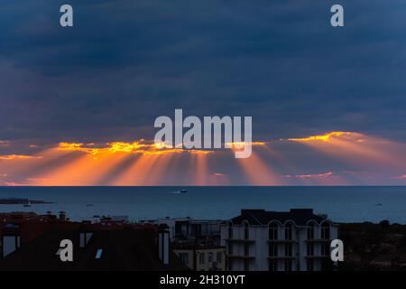 Sevastopol Crimea on September 28, 2021. Tramonto sul mare e le case. I bellissimi raggi arancioni del sole si infrangono attraverso le nuvole di tempesta blu scuro. La sh Foto Stock