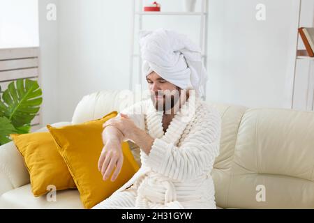 L'uomo bearded sfrega mano crema sulle sue mani. Spa, cura del corpo e della pelle per l'uomo concetto Foto Stock