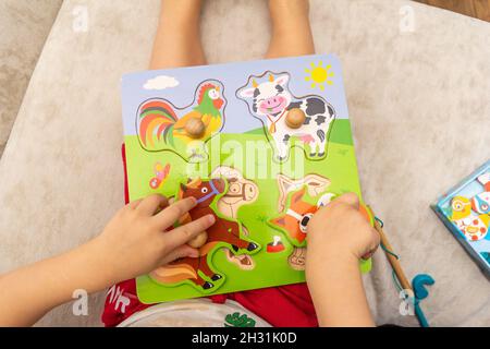 un bambino gioca con puzzle di legno con animali Foto Stock