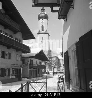 Blick in einen Ortskern mit Kirche und Ladenlokalen, Deutschland 1930er Jahre. vista di un centro citta' con la torre campanaria e una farmacia, Germania 1930s. Foto Stock