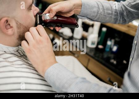 il cliente nel salone taglia la barba, un uomo visita un barbiere Foto Stock