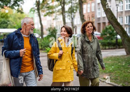 Ritratto di nonni felici con nonno di preteen che cammina insieme portelli in strada della città Foto Stock