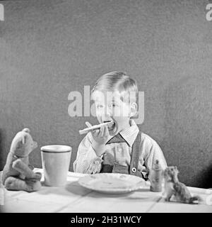 Ein kleiner Junge isst ein Butterbrot, Deutschland 1951. Un ragazzino che mangia il pane e il burro, Germania 1951. Foto Stock