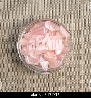 Diversi pezzi di quarzo rosa lucido su sfondo grigio testurizzato. Vista dall'alto della fotografia a colori dal minimo Foto Stock