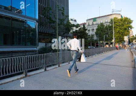 giovane afro che corre per strada con borse di carta in mano Foto Stock