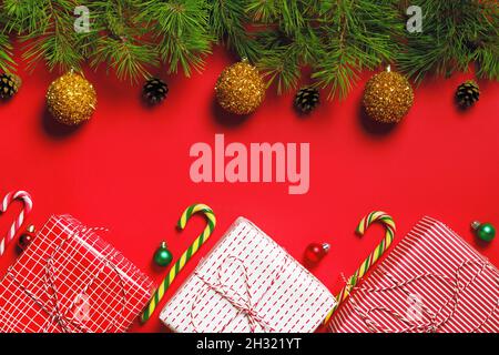 Banner composizione Natale. Scatole di Natale con regali e rami di abete su sfondo rosso. Spazio di copia con vista dall'alto in posizione piana Foto Stock