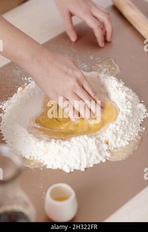 Mani di donna che mescolano gli ingredienti per la pasta di mooncake su tavola di plastica Foto Stock