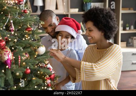 Felici genitori afroamericani che decorano albero di Natale con figlio. Foto Stock