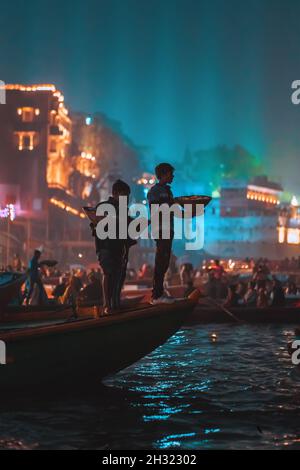 18.12.2019, Varanasi, India. Un gruppo di persone con offerte nelle loro mani, galleggiando su una barca sul fiume. Notte, festa religiosa. Foto Stock