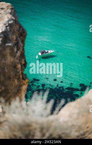 Barca solitaria ormeggiata in laguna bounty, Capo Fiolent a Balaklava, Sevastopol, Russia. Vista dalla cima della roccia. Acqua di mare verde smeraldo azzurro Foto Stock