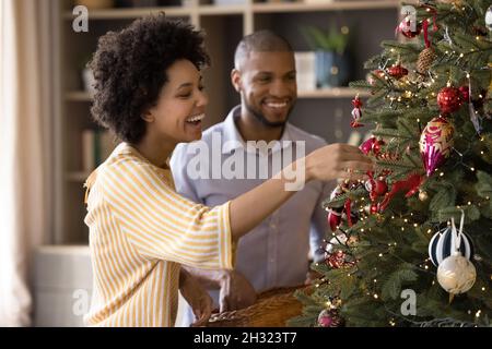Felice coppia mista di famiglia di gara che decorano albero di Natale. Foto Stock