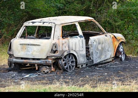 Rubato torched e bruciato tre porte hatchback BMW Mini auto relitto & scaricato in remoto rurale agricoltura località su terra bruciata in Essex Inghilterra Regno Unito Foto Stock