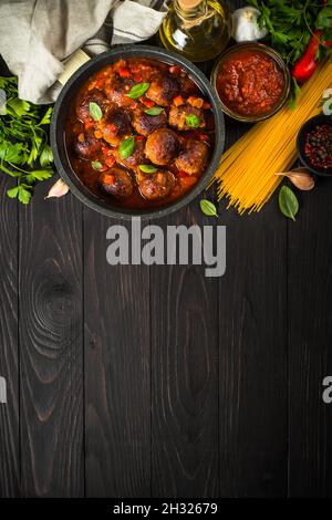 Polpette in salsa di pomodoro e pasta su tavola di legno scuro. Foto Stock