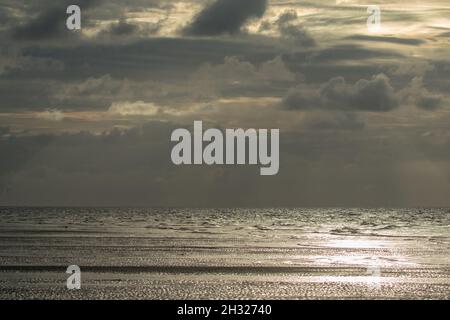 Una luce argentea e le nubi drammatiche come il sole tramonta sul Mare di Nort sulla Costa Nord Norfolk. REGNO UNITO Foto Stock