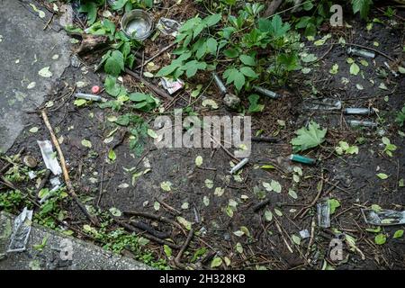un gruppo di siringhe usate e sporche usciti dopo l'iniezione del farmaco giacenti sul terreno all'aperto Foto Stock