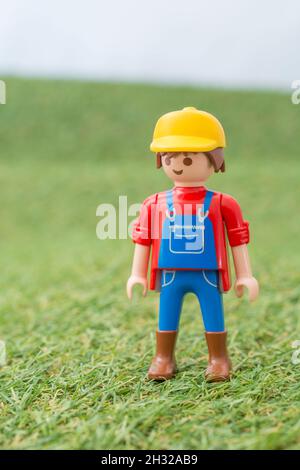 Piccolo giocattolo personaggio contadino Playmobil in piedi in 'campo' di faux / fake erba. Per la produzione di alimenti nel Regno Unito, da azienda agricola a forca, da campo a forca/da campo a piastra. Foto Stock