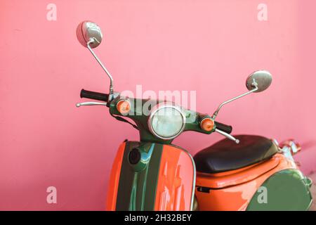 Scooter colorato parcheggiato sulla strada su sfondo rosa parete. Concetto di condivisione affitto Foto Stock