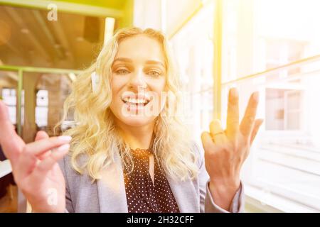 Donna d'affari bionda con cuffie in videoconferenza in ufficio Foto Stock