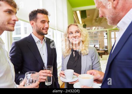 Il team di start-up e i manager che parlano poco durante una pausa caffè in ufficio Foto Stock
