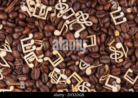 Sfondo concettuale astratto fatto di chicchi di caffè misti e note musicali in legno. Foto Stock