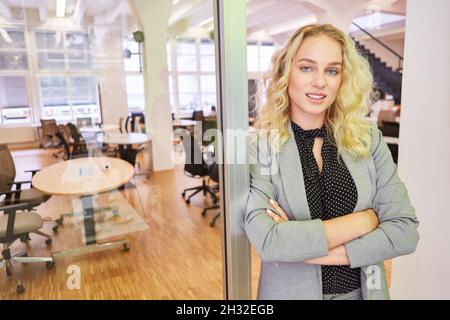 La giovane donna come fondatrice di start-up è in piedi in ufficio con le braccia incrociate Foto Stock