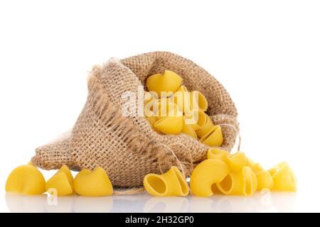 Pasta cruda giallo brillante in sacchetto di iuta, primo piano, isolato su bianco. Foto Stock