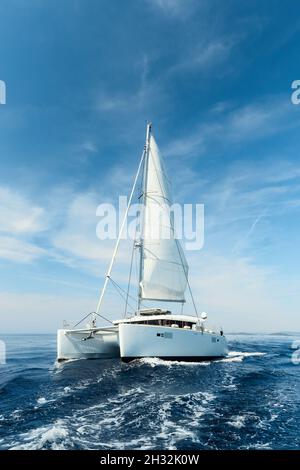 Catamarano di lusso in barca a vela bianca sul mare azzurro in una giornata estiva soleggiata. Viaggi, yachting, regate concetto Foto Stock