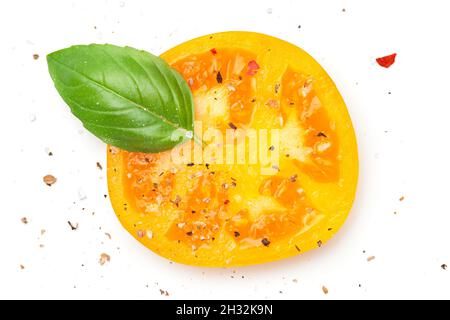 Fetta di pomodoro giallo con basilico e spezie, pepe, sale. Composizione isolata su sfondo bianco. Vista dall'alto. Disposizione piatta Foto Stock