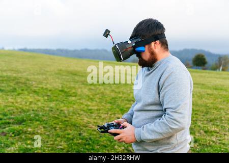 Uomo bearded usando un drone con telecomando che indossa occhiali di realtà virtuale fare foto e video . Giovane ragazzo che si diverte con il nuovo tecnolog vr Foto Stock