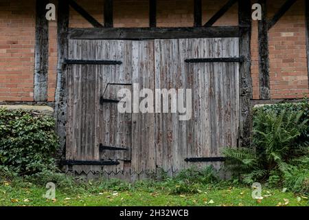La porta del vecchio fienile in legno era incantevole, con cerniere in metallo e una porta di accesso più piccola Foto Stock