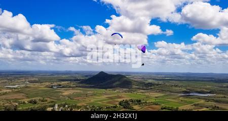 Due parapendio sui campi colorati contro un cielo nuvoloso Foto Stock